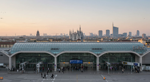 Milan Linate Airport entrance with modern glass terminal building and Milano city background